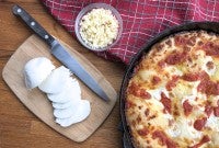 Mozzarella and jack cheeses beside baked pizza.